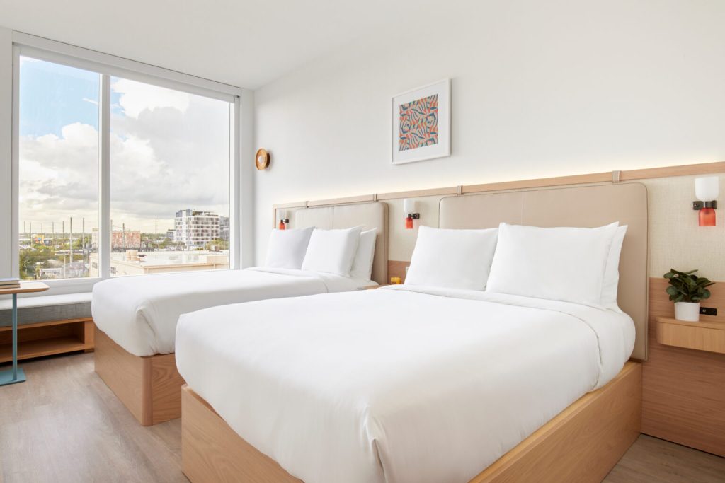 Arlo Wynwood room with two double beds and a large city-view window.