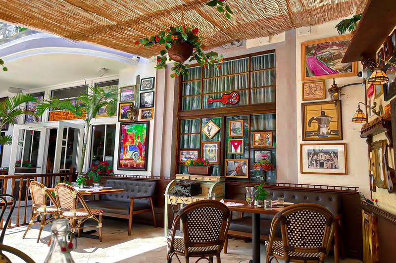 Hotel Chelsea South Beach patio with vintage décor, framed art, and café seating.