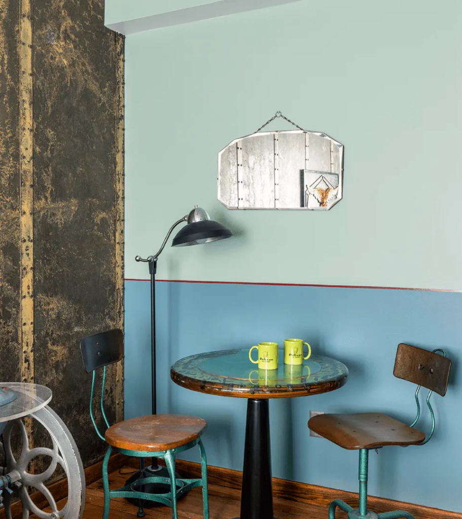 Pelican Hotel Miami Beach room detail with vintage bistro table, industrial chairs, and retro blue wall