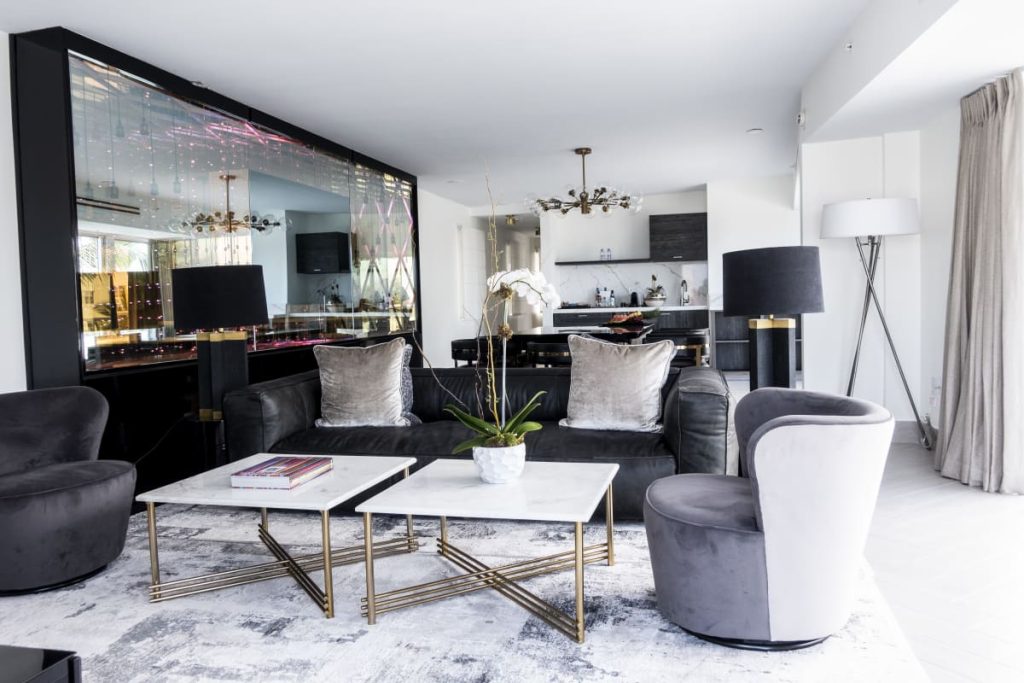 Modern suite living room at The Sagamore South Beach with black sofa, velvet chairs, and open kitchen.