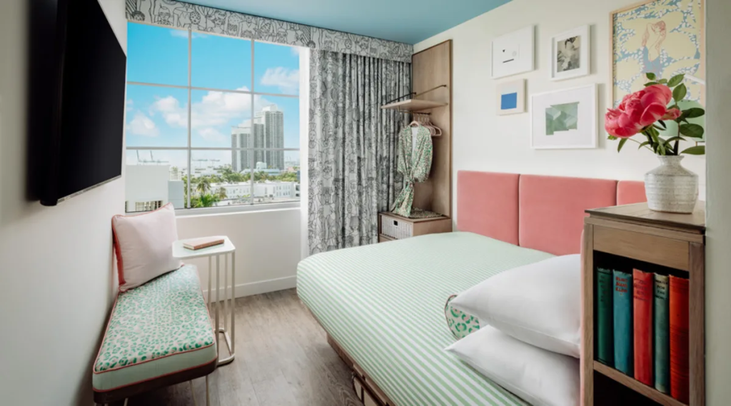 Colorful guest room at The Goodtime Hotel South Beach with city-view window and pastel decor.
