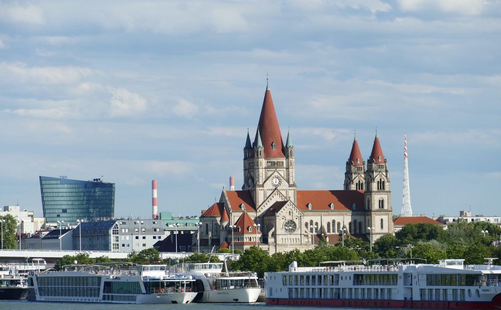 View of Vienna skyline with St. Francis of Assisi Church and Danube river cruise ships